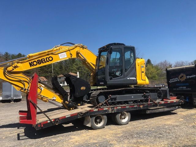 a kobelco excavator is sitting on top of a flatbed trailer