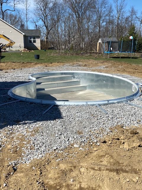 A swimming pool is being built in the dirt in a backyard