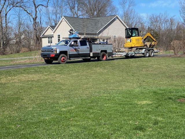 A truck is towing a yellow excavator on a trailer