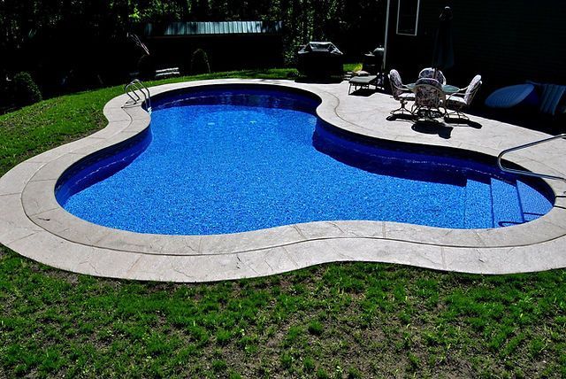 A large swimming pool is surrounded by a lush green lawn