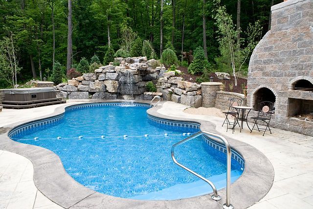 A large swimming pool with a fireplace and a waterfall