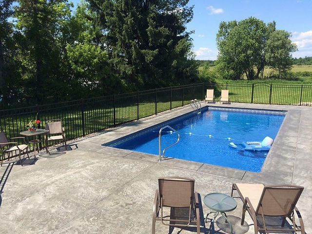 A large swimming pool is surrounded by chairs and tables
