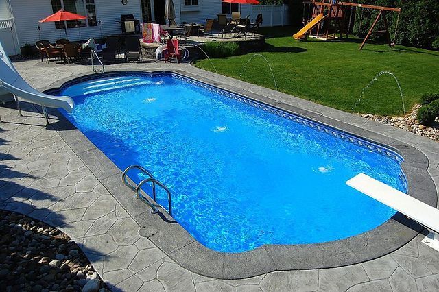 A large swimming pool with a slide in the backyard