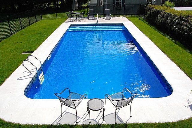 A large swimming pool surrounded by chairs and a table
