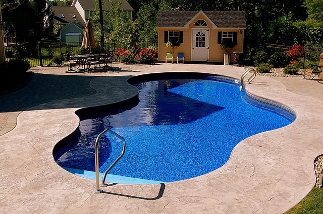 A large swimming pool with a yellow shed in the background