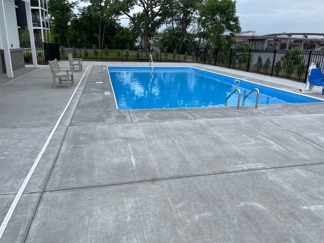 a large swimming pool is surrounded by concrete and chairs .
