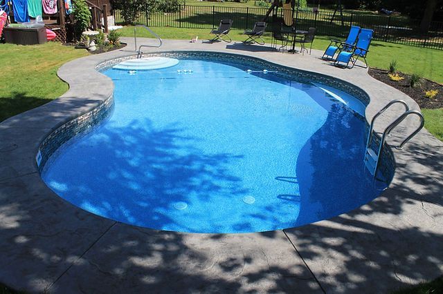 A large swimming pool is surrounded by chairs
