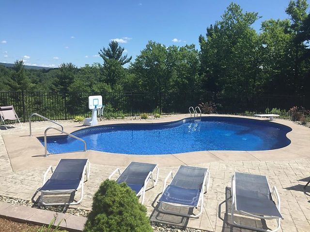 A large swimming pool surrounded by chairs and a basketball hoop