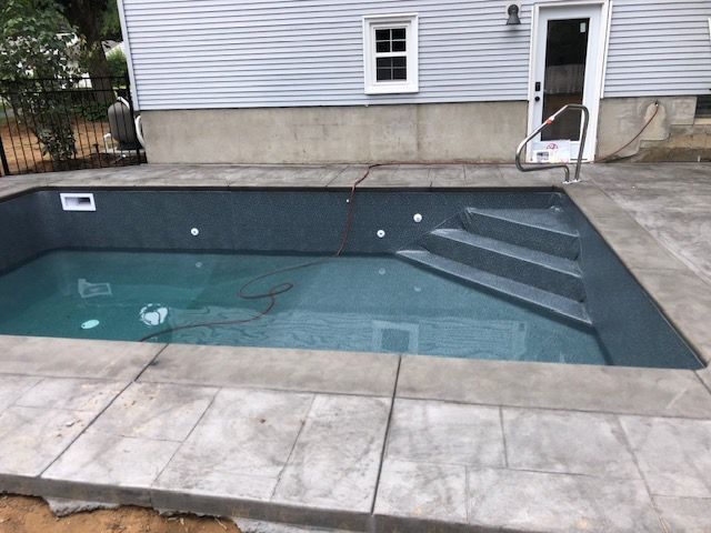 a swimming pool with stairs and a house in the background