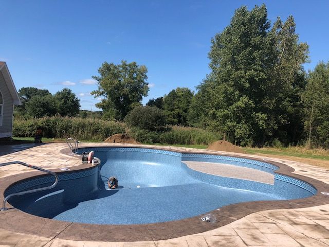 a person is swimming in a large swimming pool surrounded by trees .