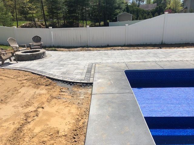 a swimming pool with stairs and a fire pit in the backyard .