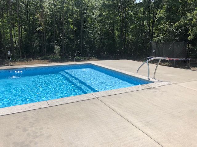 a large swimming pool is surrounded by trees on a sunny day .