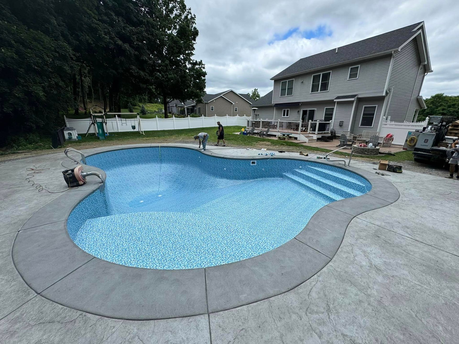 A large swimming pool is being built in the backyard of a house.