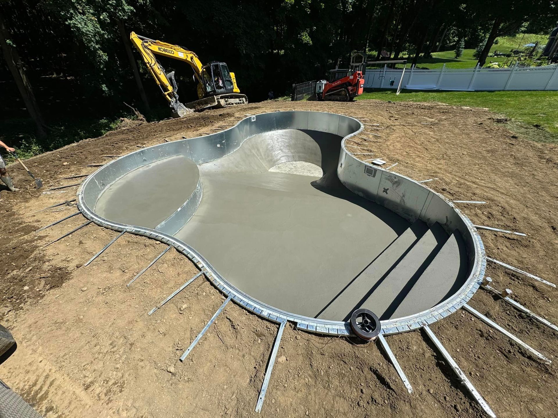 A large swimming pool is being built in a backyard.