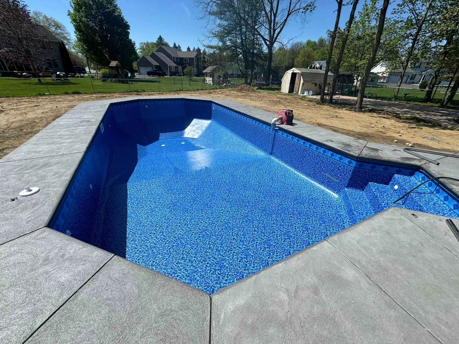 A large swimming pool is being built in the backyard of a house.