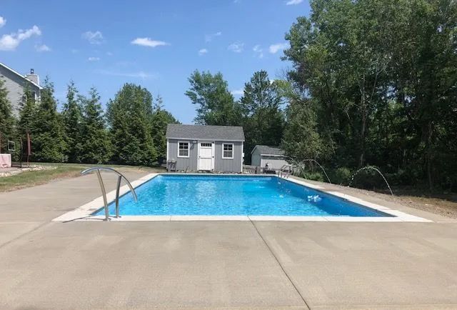 a large swimming pool is in the backyard of a house