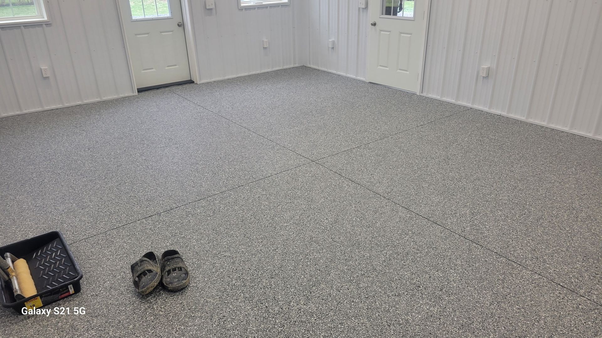 Empty gray room with double doors and a pair of shoes on the carpeted floor