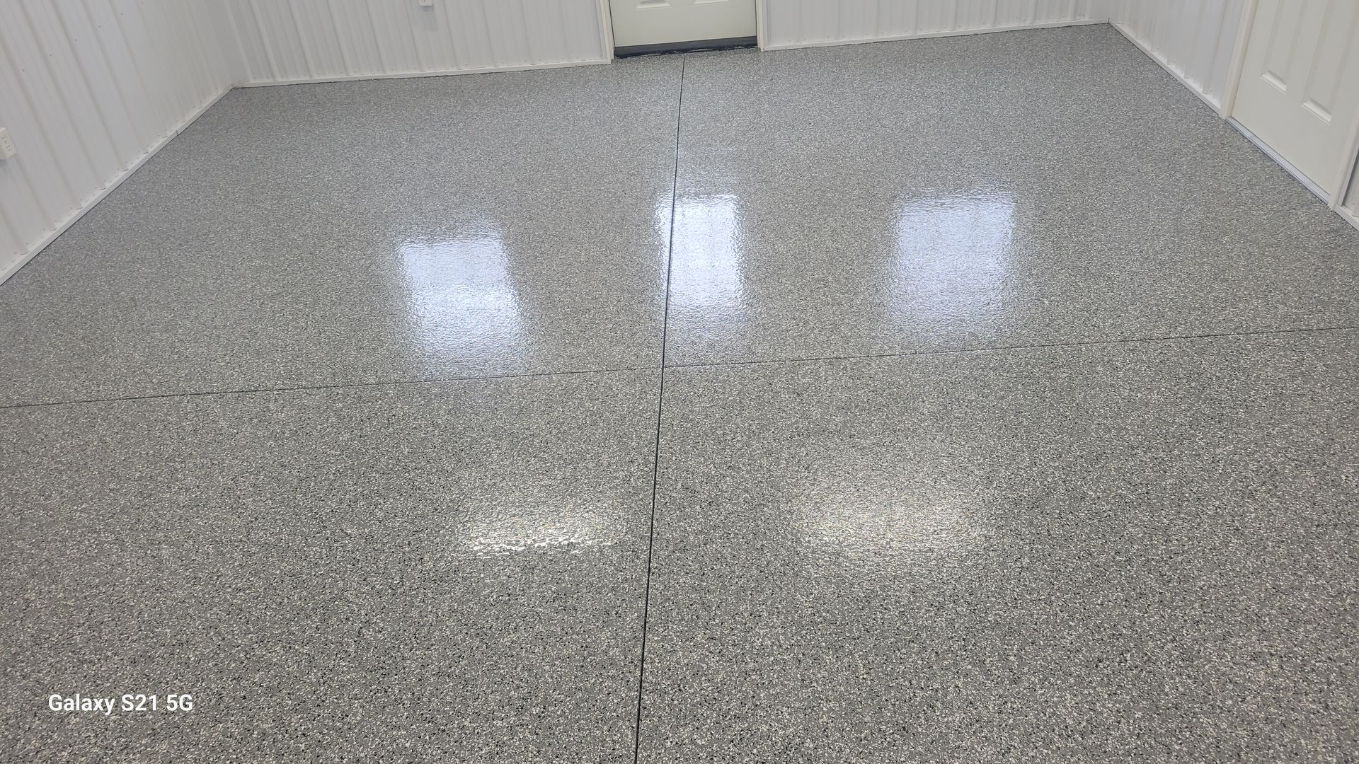 Empty gray speckled floor with bright window reflections in a room