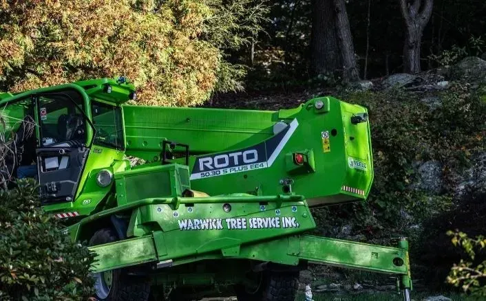 Green Merlo ROTO telehandler from Warwick Tree Service on a hillside.