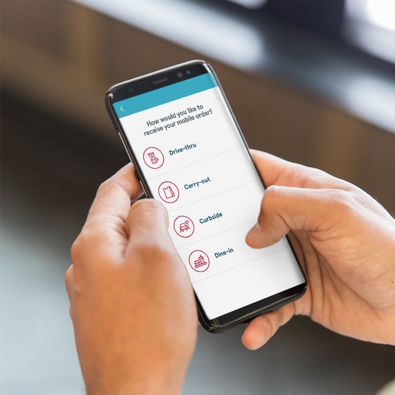 Hands holding a smartphone with options: delivery, carry-out, curbside, and dine-in.