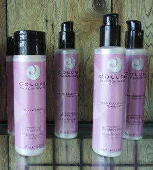 Bottles of COLURE shampoo and conditioner with pink and white labels, arranged on a shelf.