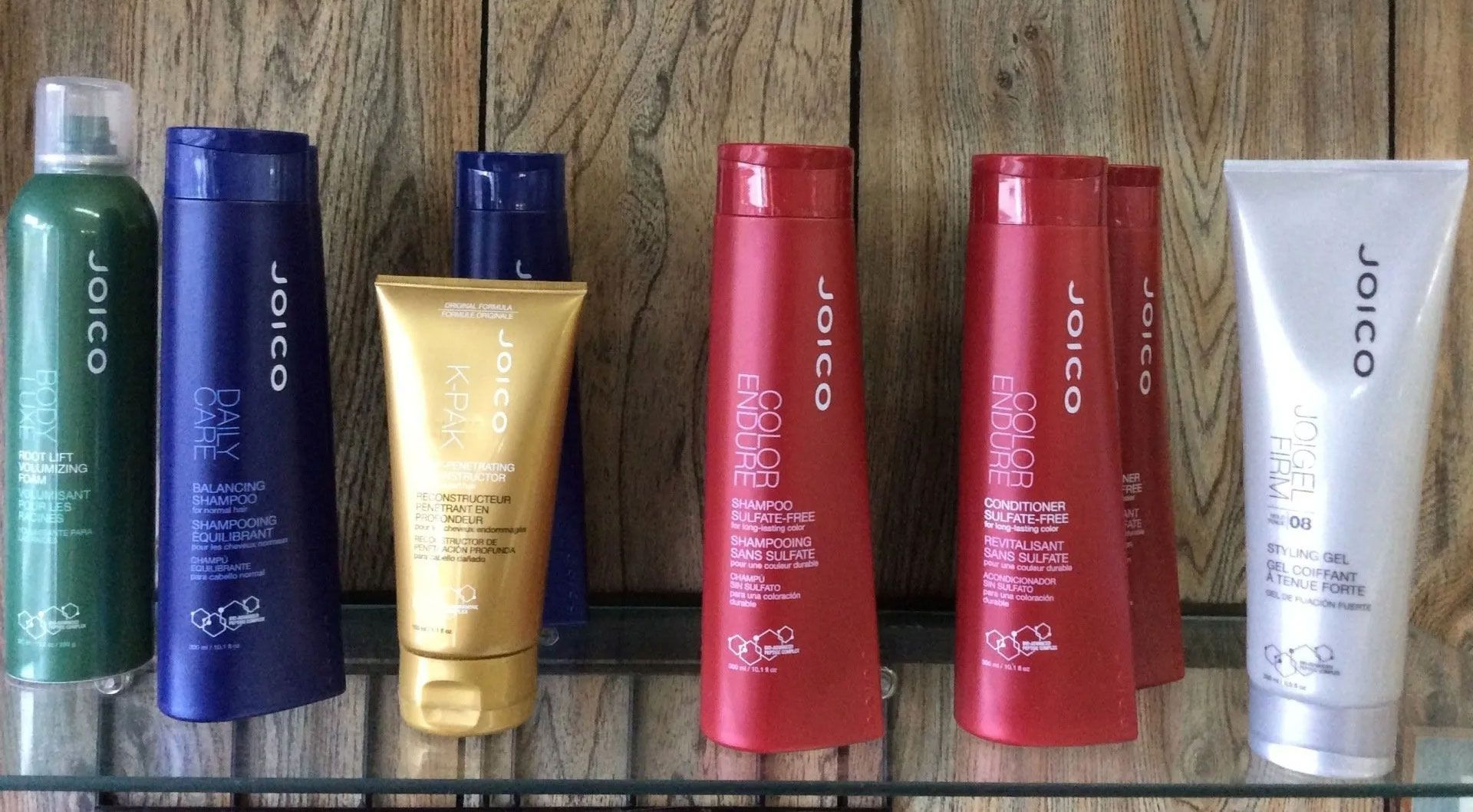Shelves displaying various bottles of Joico hair products in different colors: green, blue, gold, red, and silver.