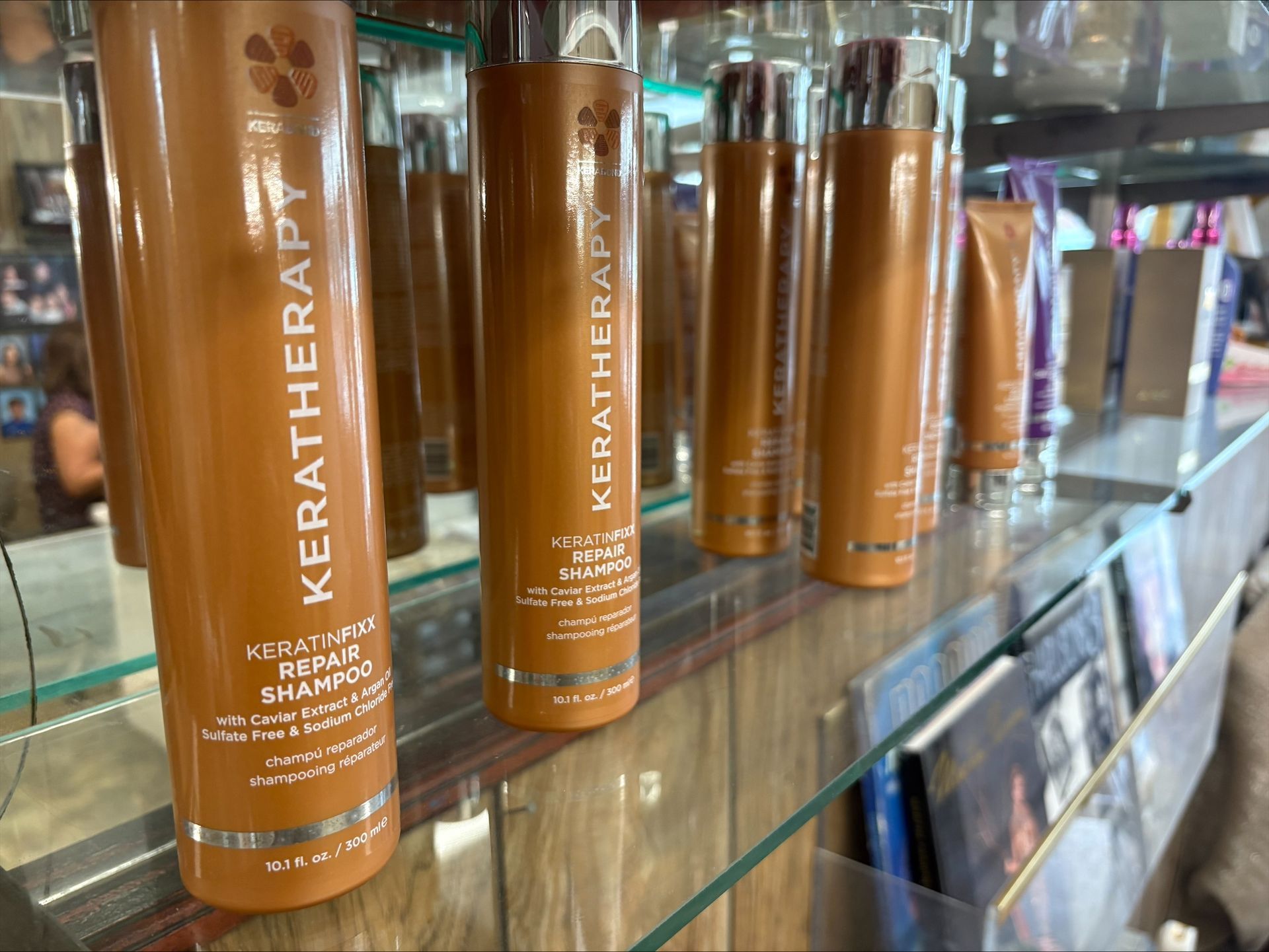 Bottles of Keratherapy hair products on a shelf, with a reflection in the mirror.