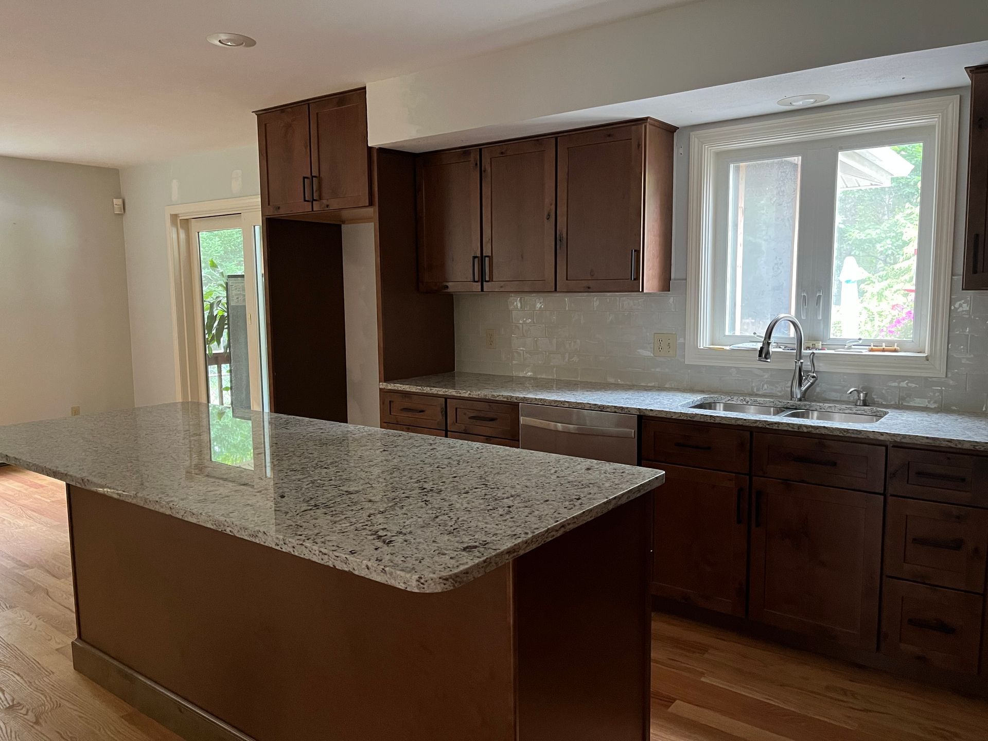 Kitchen with granite island, dark wood cabinets, and a window over the sink.