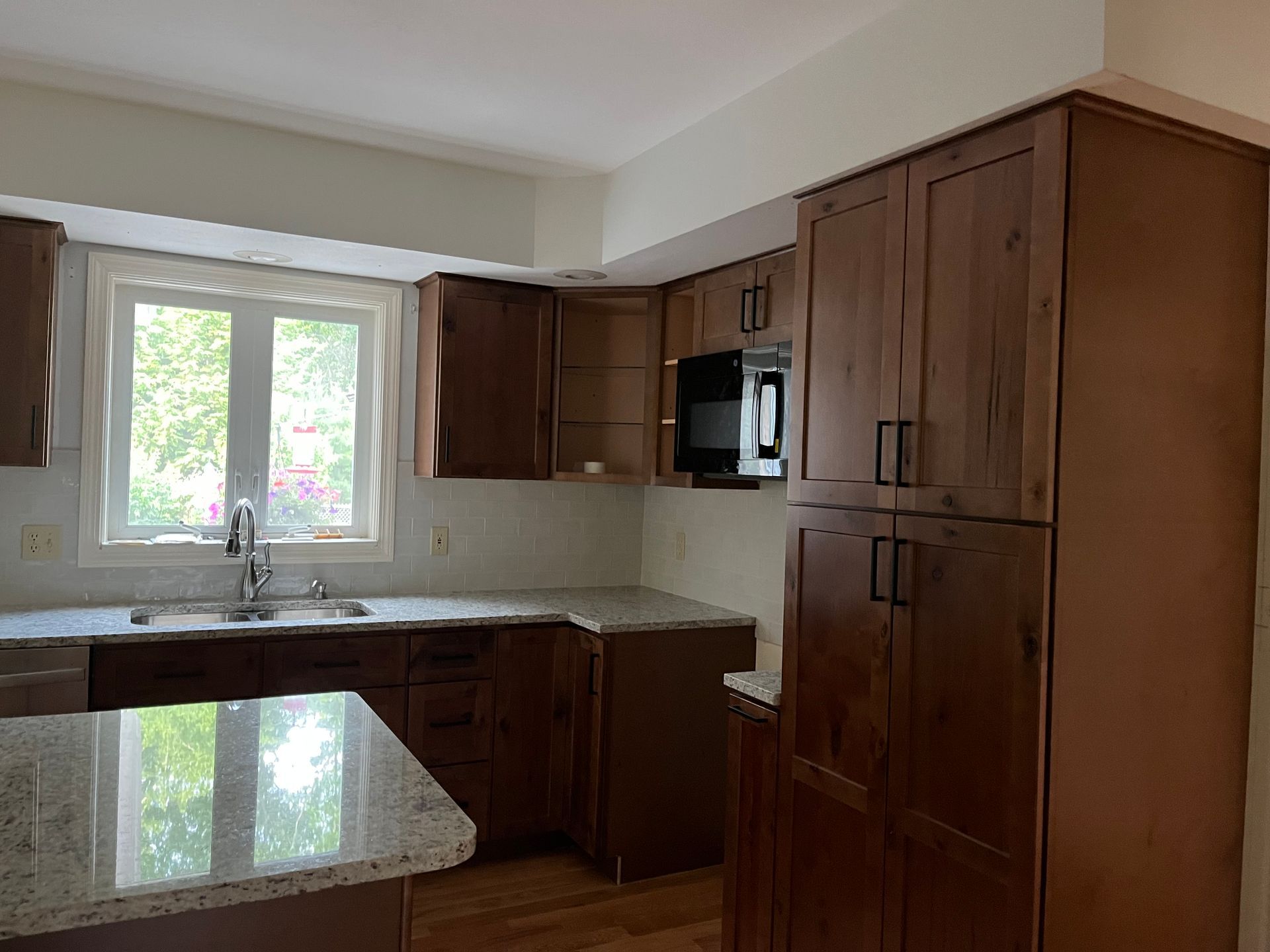 Kitchen with brown cabinets, white countertops, and a window.