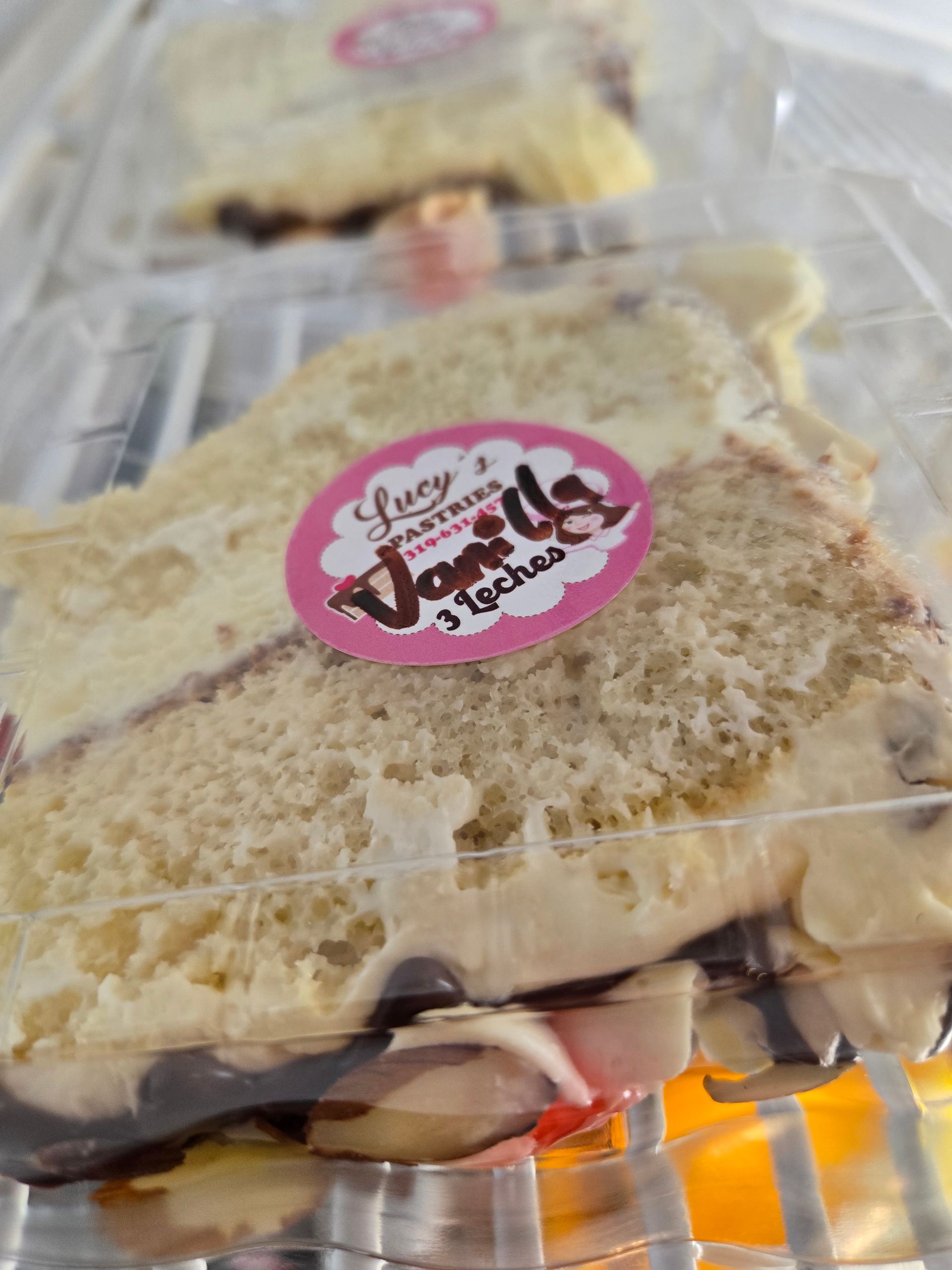 A slice of cake in a plastic container with a sticker that says vanilla 3 inches