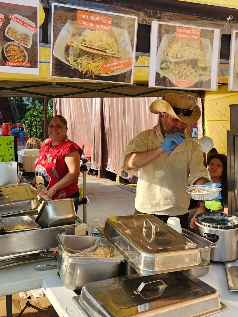 A man in a cowboy hat is cooking food at a food stand.