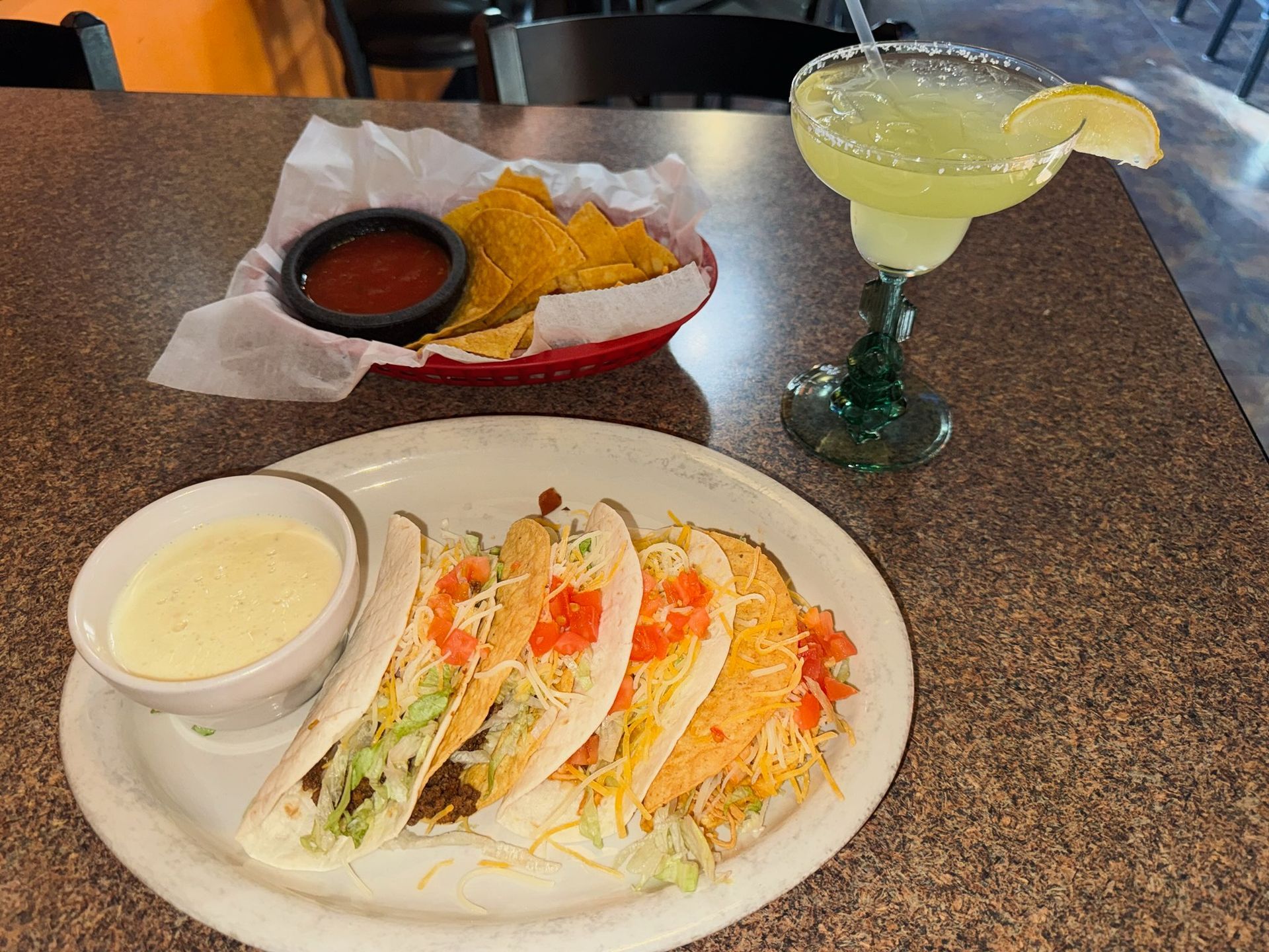 A plate of tacos and a margarita on a table.