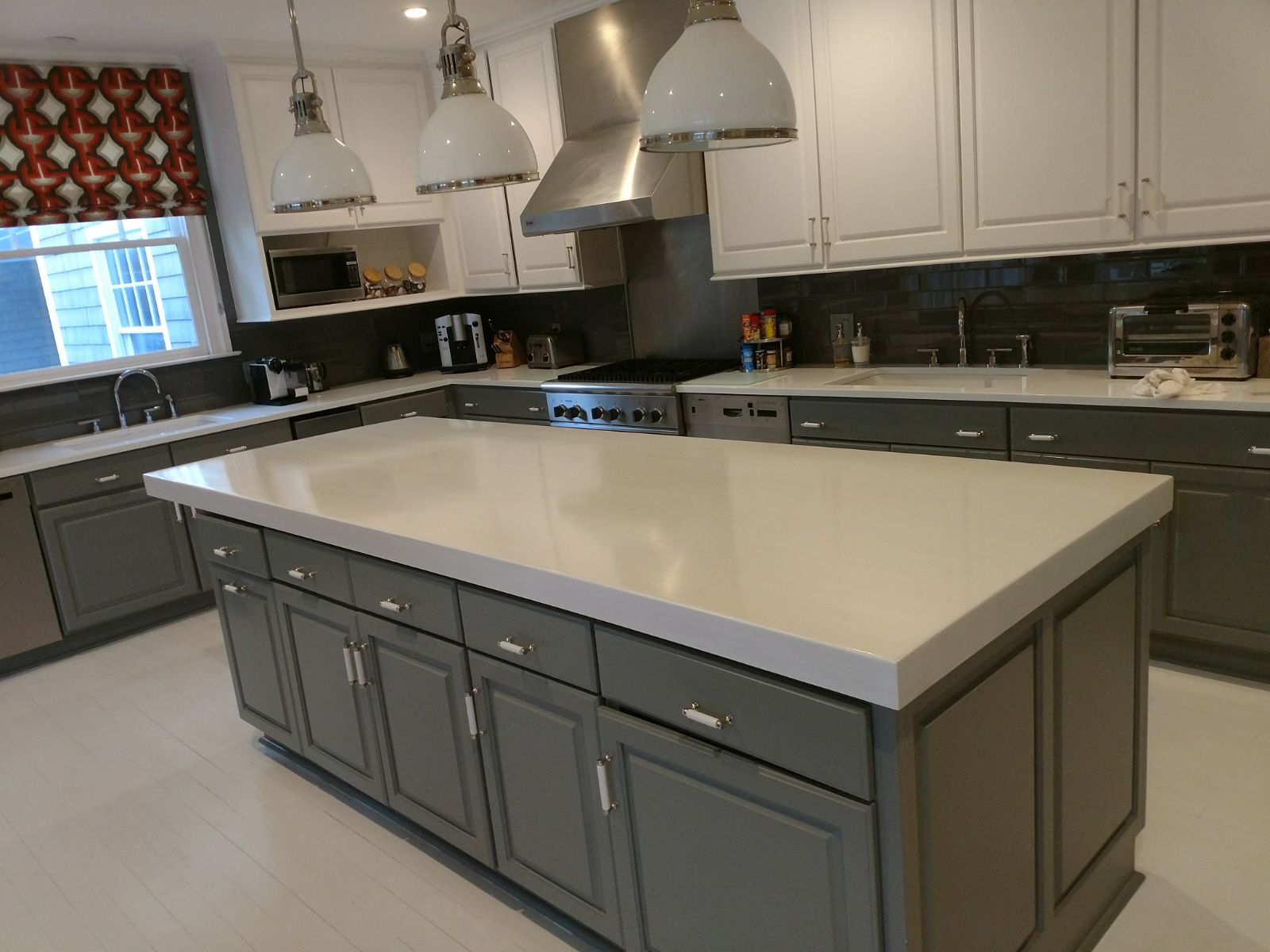A kitchen with gray cabinets and white counter tops
