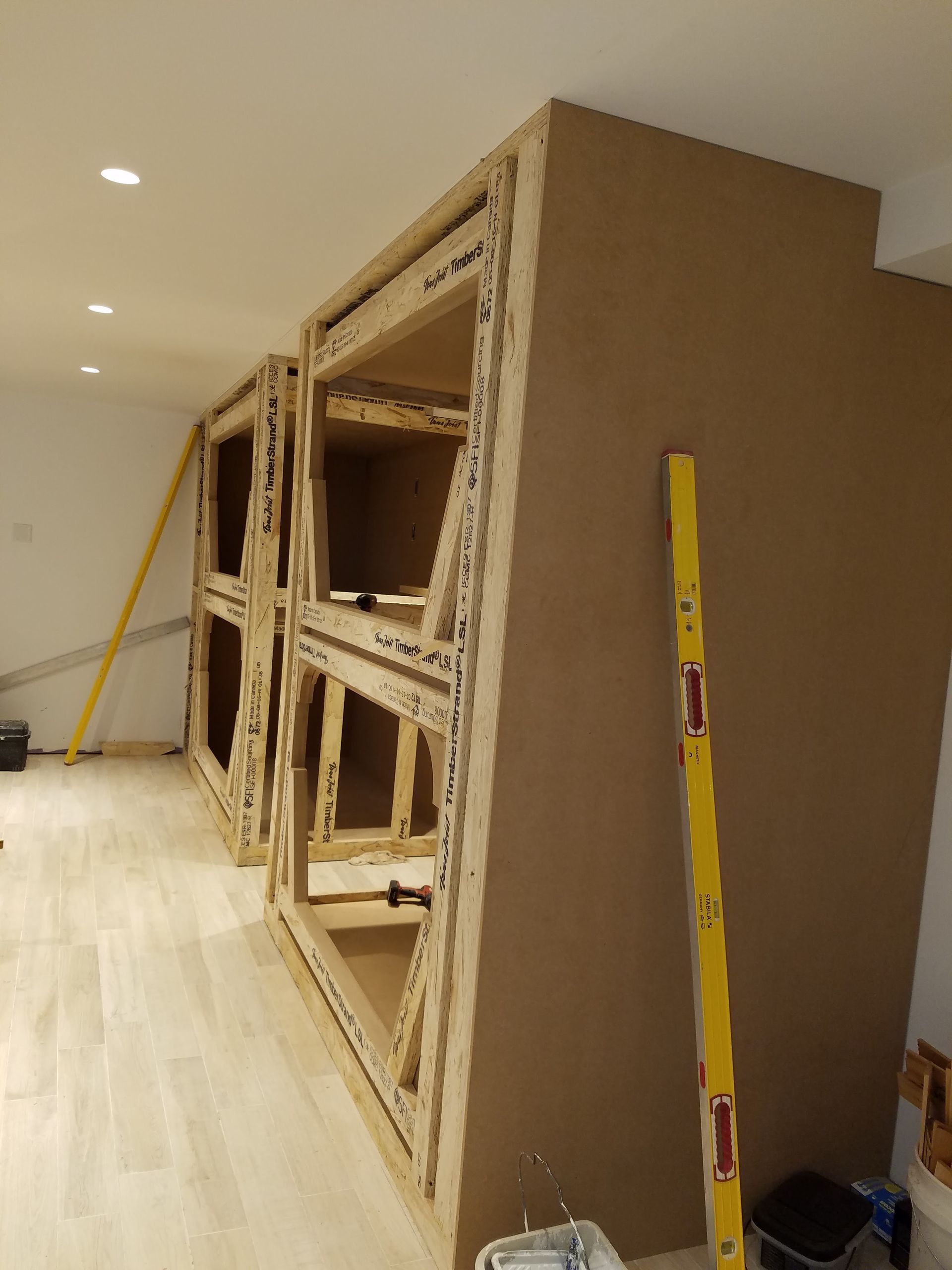 A wooden cabinet is being built in a room with a yellow level.