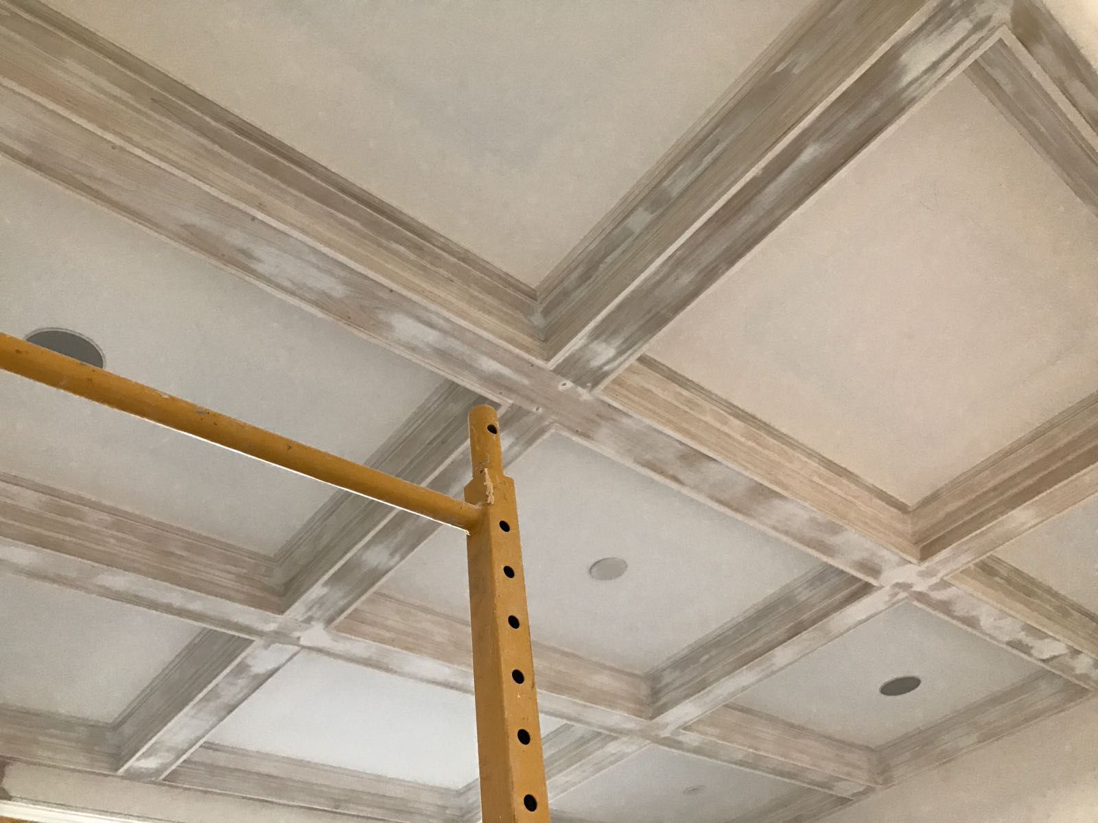 A ceiling is being painted in a room with scaffolding.
