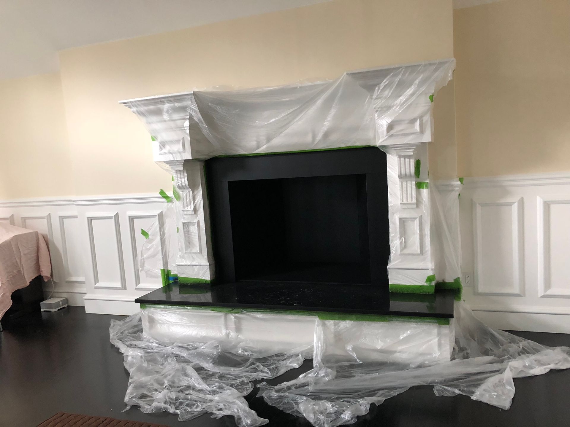 A fireplace is covered in plastic wrap in a living room.