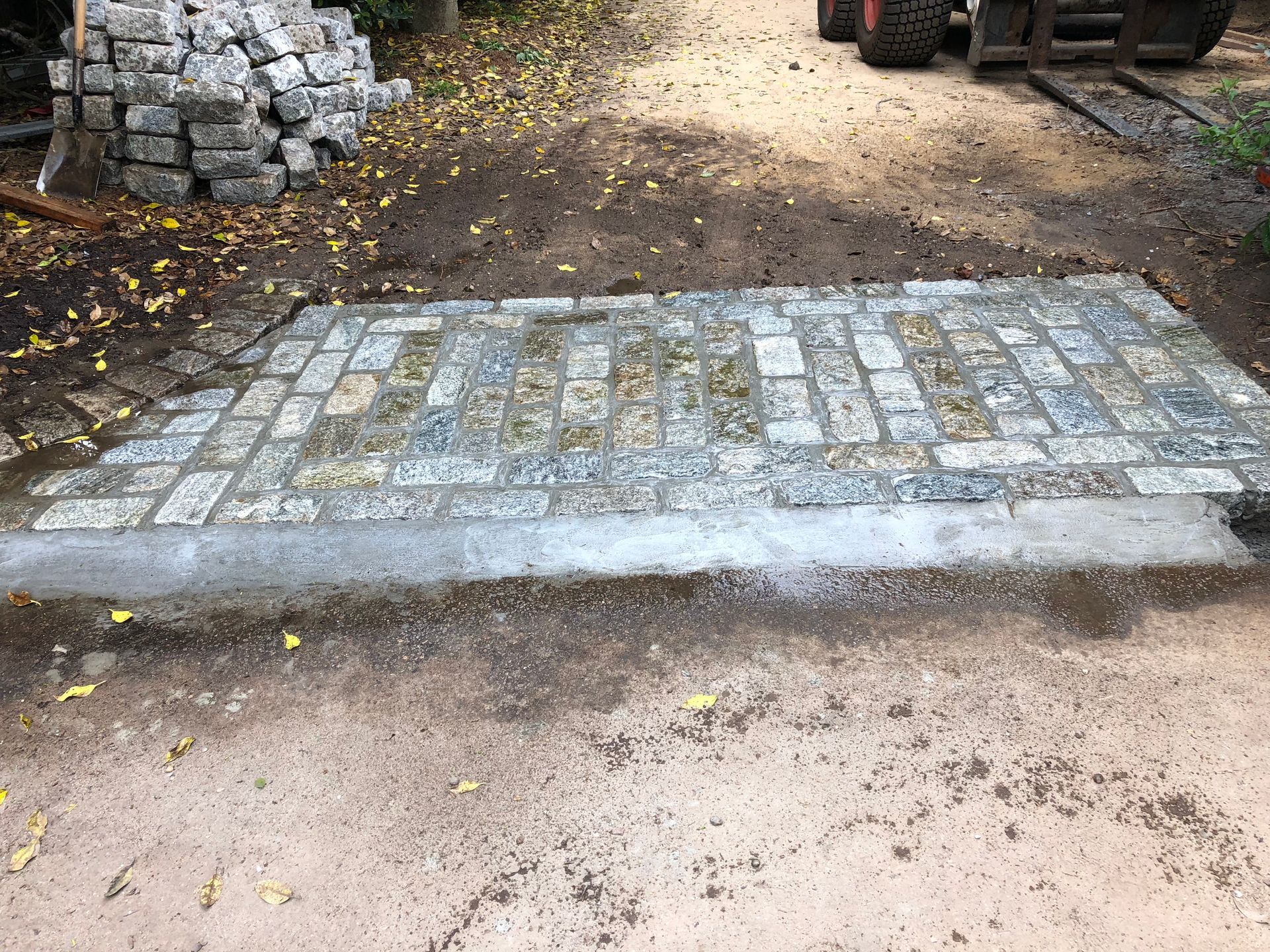 A brick walkway is being built on a dirt road.