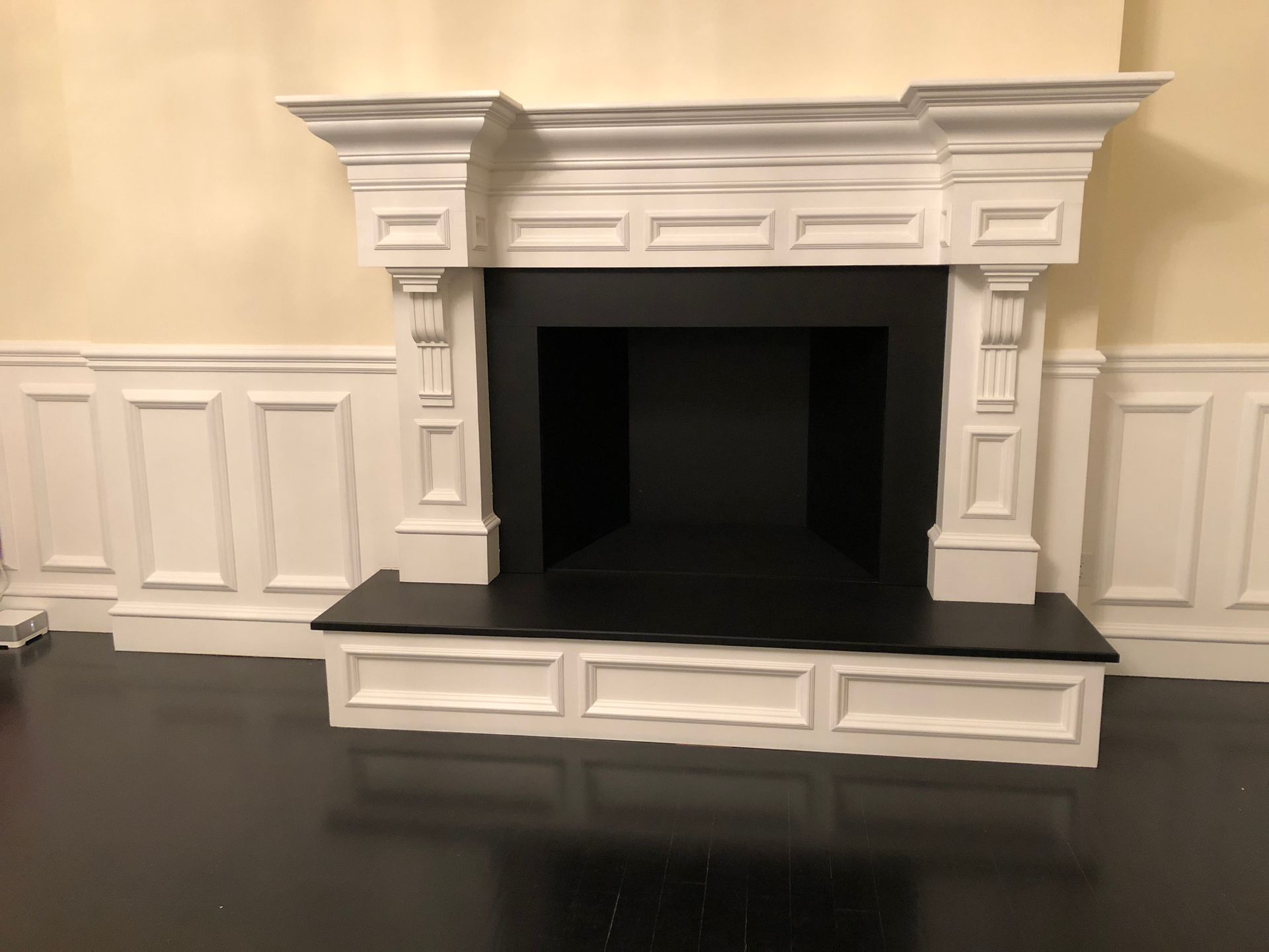 A fireplace with a black mantel and white trim in a living room