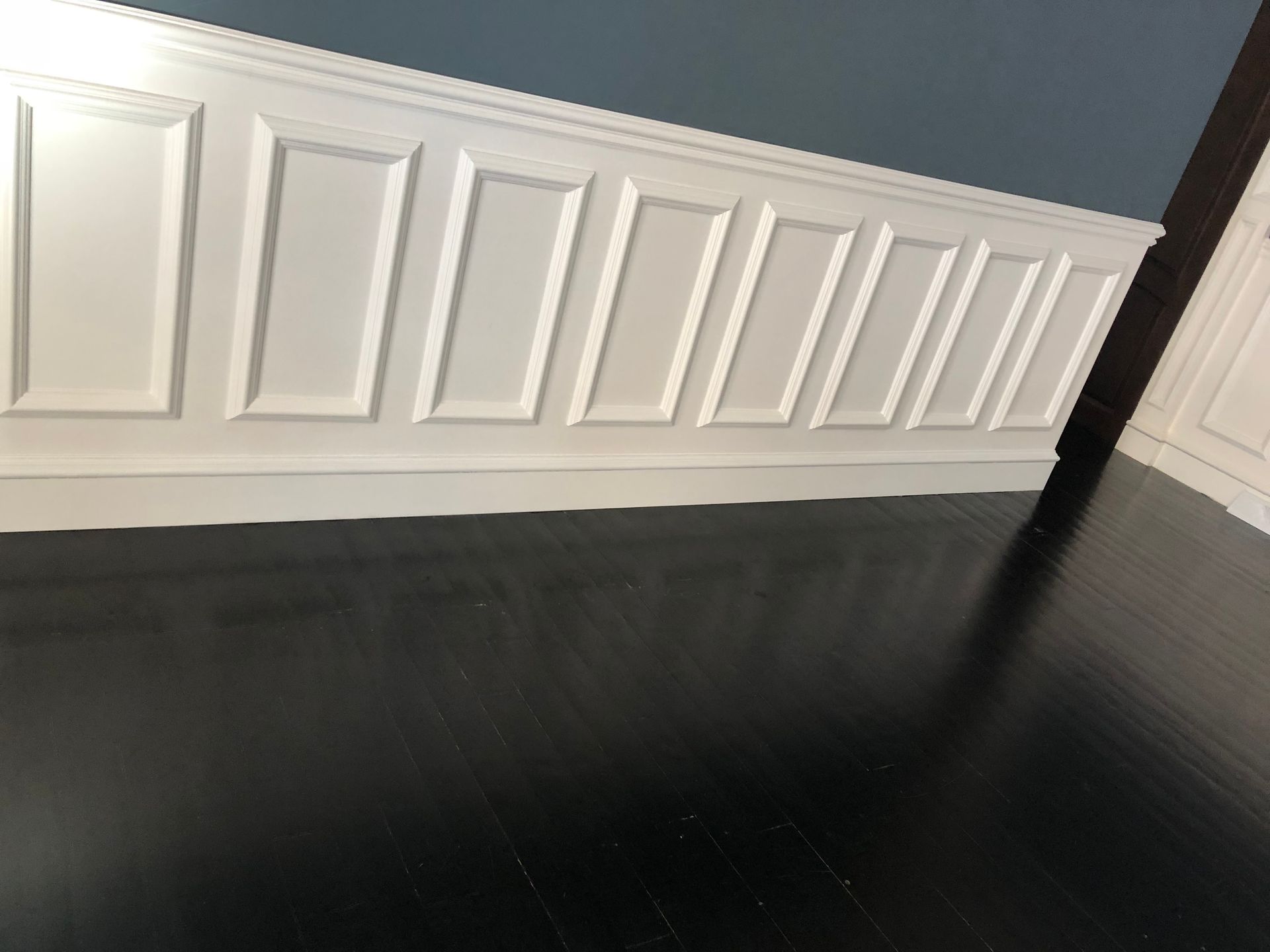 A room with a black floor and white paneling on the wall.