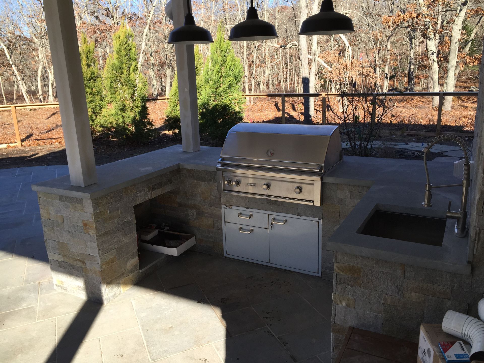 An outdoor kitchen with a grill and a sink