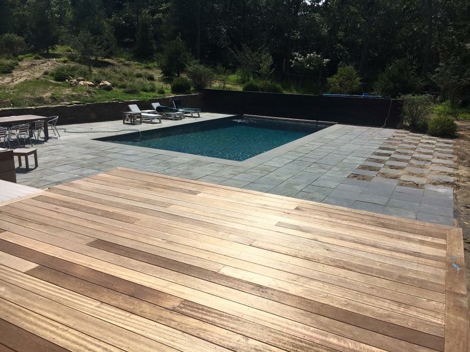 A large swimming pool is surrounded by a wooden deck.