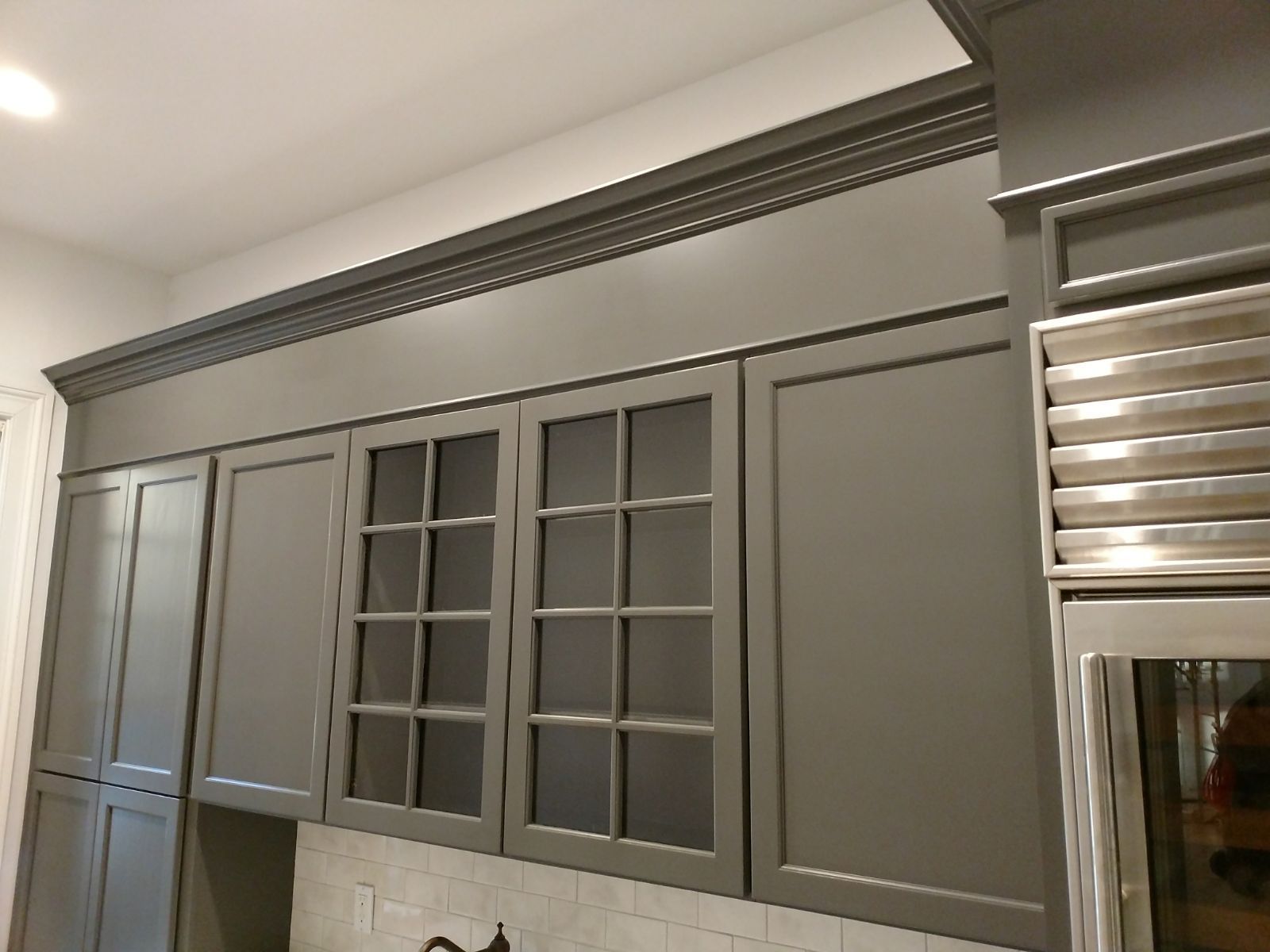 A kitchen with gray cabinets and stainless steel appliances.
