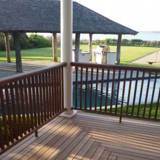 A wooden deck with a railing overlooking a swimming pool.