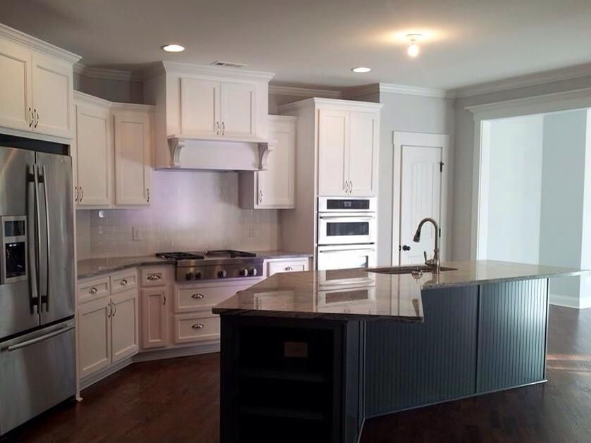 White kitchen with dark island, stainless steel appliances, and granite countertops.