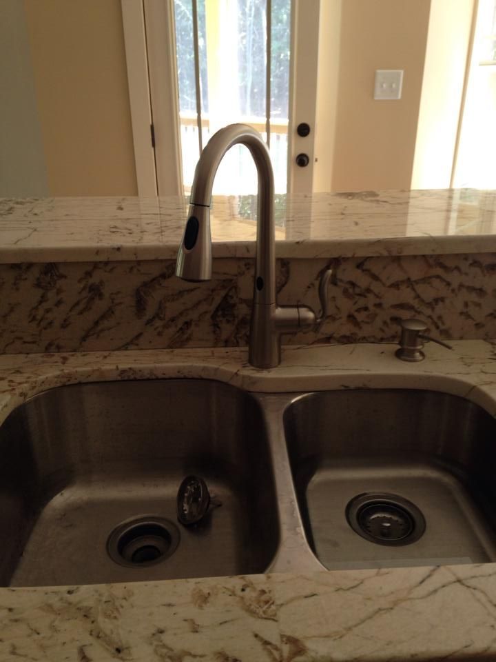 Stainless steel kitchen sink with faucet on granite countertop.