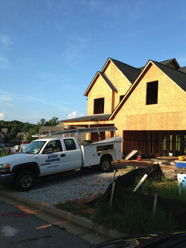 Truck parked at a house under construction, framed with bare wood. Blue sky.