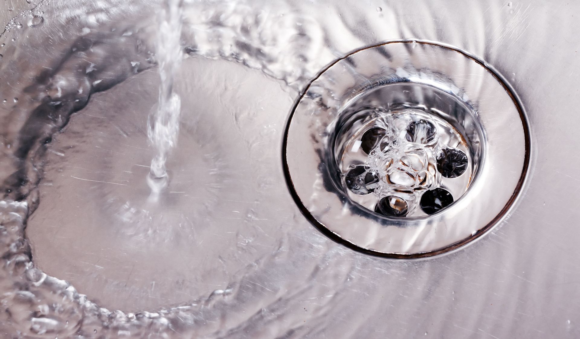 Water flowing into a silver sink drain.
