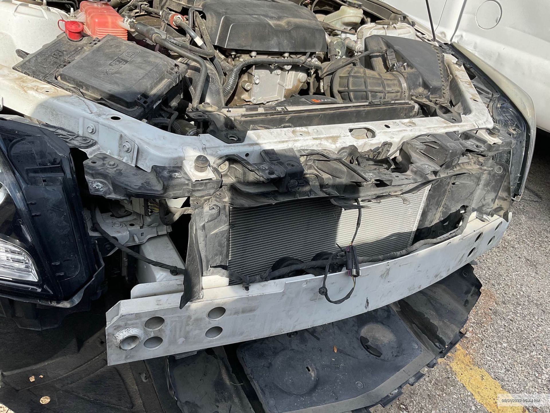 White car with significant front-end damage, exposing engine components.
