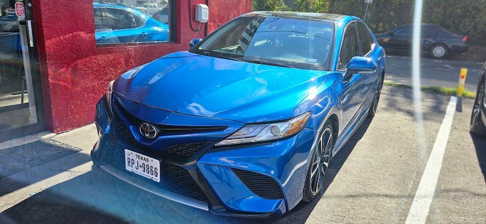 Blue Toyota Camry parked in a parking spot in front of a building.