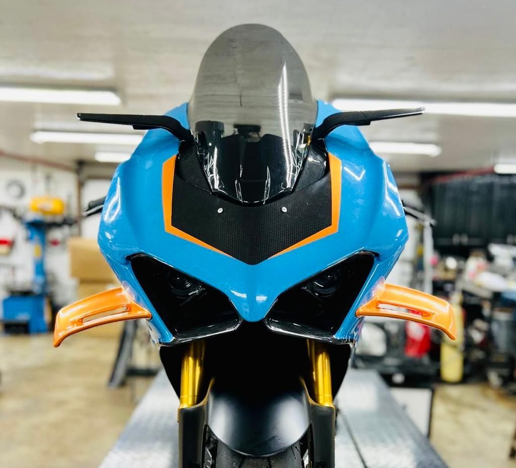 Blue and orange sport motorcycle front view, with a black windscreen and carbon fiber details.